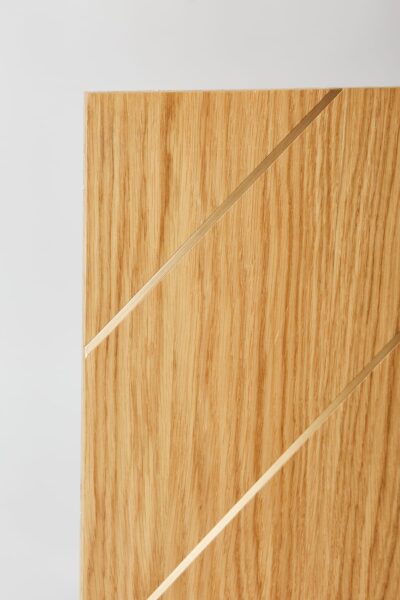 Widok panelu drewnianego z bliska. Błyszczące dwie listwy mosiężne.