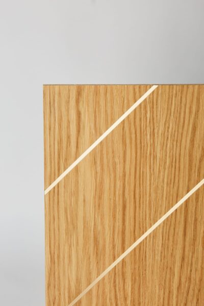 Zbliżenie na powierzchnię panelu drewnianego z listwami mosiężnymi.