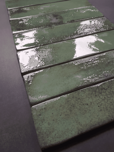 Zestaw zielonych płytek ceramicznych w formacie 6x25cm, metalizowanych.