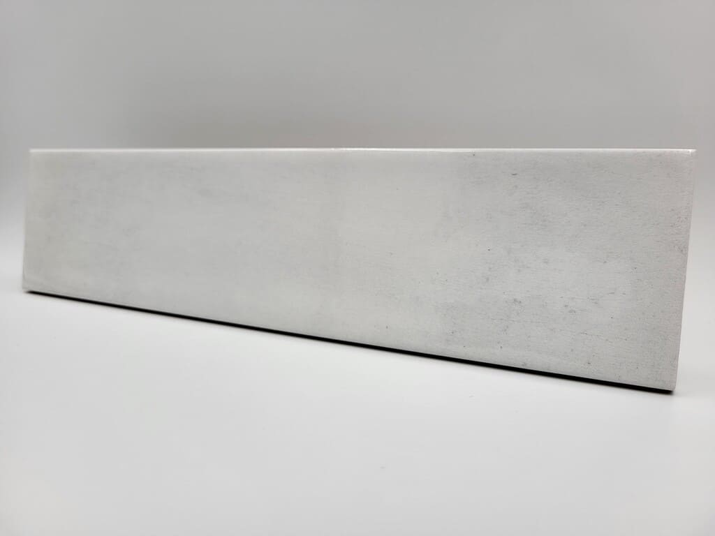 Płytka cegiełka biała połysk - Harmony Bari White 6x24,6 cm. Kafelka cegiełka do łazienki lub kuchni na ścianę z widocznymi ciemnymi przetarciami.
