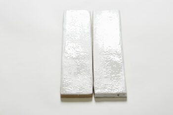 Dwie płytki cegiełki białe, z widoczną błyszczącą powierzchnią, oblaną nierównomiernie szkliwem w zimnym odcieniu bieli - Peronda Harmony Legacy snow 6x25cm. Kafelki ścienne do kuchni, łazienki.