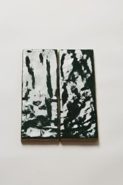 Dwie płytki łazienkowe, zielone, cegiełki na ścianę Harmony RIAD GREEN/6,5X20. Zdjęcie pokazuje niesamowitą powierzchnię zielonych płytek, które są błyszczące i nieregularne, sprawiające wrażenie ręcznie wykonanych.