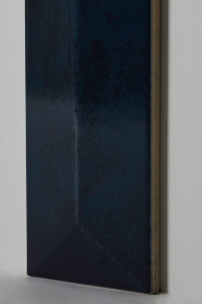 Fazowane płytki na ścianę - APE Reality spectrum river 7,5x30cm. Płytki 3D w kolorze ciemnoniebieskim i błyszczącej powierzchni. Doskonale wyglądają w eleganckim salonie na ścianie.