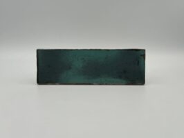 Niebieskie kafle łazienkowe - Estudio Amazonia Sapphire 6,5x20 cm. Cegiełki ceramiczne ścienne w połysku, z rdzawymi przebarwieniami.