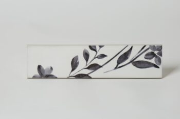 Glazura w kwiaty - Peronda Harmony Aqua Anthracite decor 6x24,6 cm. Płytki ceramiczne na ścianę z motywem kwiatowym w kolorze ciemnoszarym na białym błyszczącym tle.