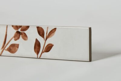 Glazura z motywem roślinnym - Peronda Harmony Aqua Brown decor 6x24,6cm. Płytki z białą powierzchnią i brązowym motywem kwiatowym.