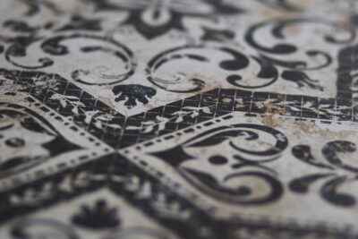 Płytki podłogowe, dekoracyjne - Absolut Keramika Mindanao Decor . Powierzchnia płytki imitującej kamień z widocznym czarnym wzorem.