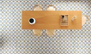Wzorzysta podłoga w kuchni - Peronda Harmony LENOS MIRTOS 22,3x22,3. Rzut z góry na podłogę wzorzystą, ceramiczną podłogę i drewniany stół.