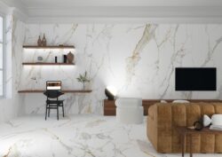 Białe płytki imitujące marmur - Museum Praline Gold. Hiszpańskie, ekskluzywne płytki marmuropodobne z szarym i karmelowym żyłkowaniem. Salon z kaflami na podłodze i ścianie.