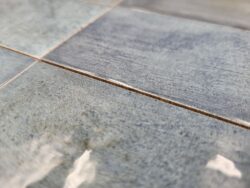 Glazura niebieska - Harmony BARI BLUE 6x24,6 cm. Błyszcząca powierzchnia płytki z widocznymi czarnymi liniami - zadrapaniami.