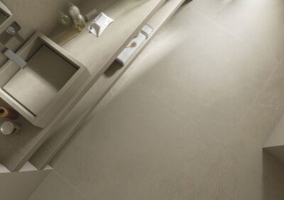 Gres antypoślizgowy - CIFRE Norwich Sand N-Plus Rect. R10. Płytki łazienkowe, imitujące beton w kolorze piaskowym na podłodze.