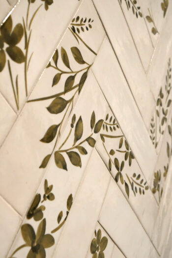 Kafelki łazienkowe - Peronda Harmony AQUA 6x24,6 cm. Białe, bazowe, błyszczące płytki oraz białe, dekoracyjne, błyszczące kafelki z zielonym motywem kwiatowym na ścianie.