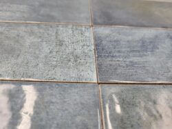 Niebieska glazura łazienkowa - Harmony BARI BLUE 6x24,6 cm. Kafelki w połyski, lekko wklęsłe z poprzecierana powierzchnia i czarnymi zadrapaniami.