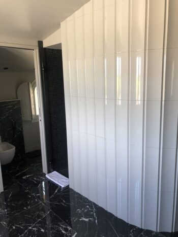 Łazienka z płytkami dekoracyjnymi na ścianie - Peronda Harmony BOW WHITE 15x45cm. Płytki łazienkowe 3D z charakterystycznym wygięciem przypominającym dachówkę w kolorze białym i połyskującą powierzchnią.