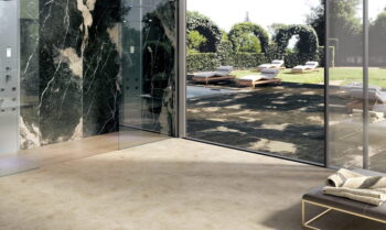 Łazienka z włoskimi płytkami na podłodze w kolorze beżowym z efektem marmuru oraz płytkami imitującymi czarny marmur.