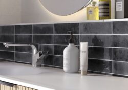 Szare, błyszczące kafelki łazienkowe - Cifre Jazba Anthracite Brillo 6x24,6cm. Płytki w małym formacie cegiełki z lekko nierówną powierzchnią z przebarwieniami.