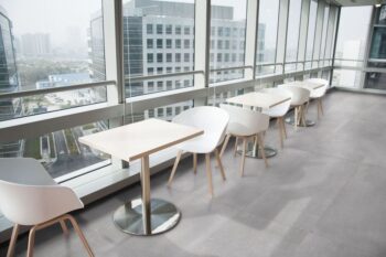 Płytki imitujące beton na podłogę 120x60 - Absolut Cozumel. Restauracja z szarymi płytkami na podłodze. Białe krzesła, białe stoliki.